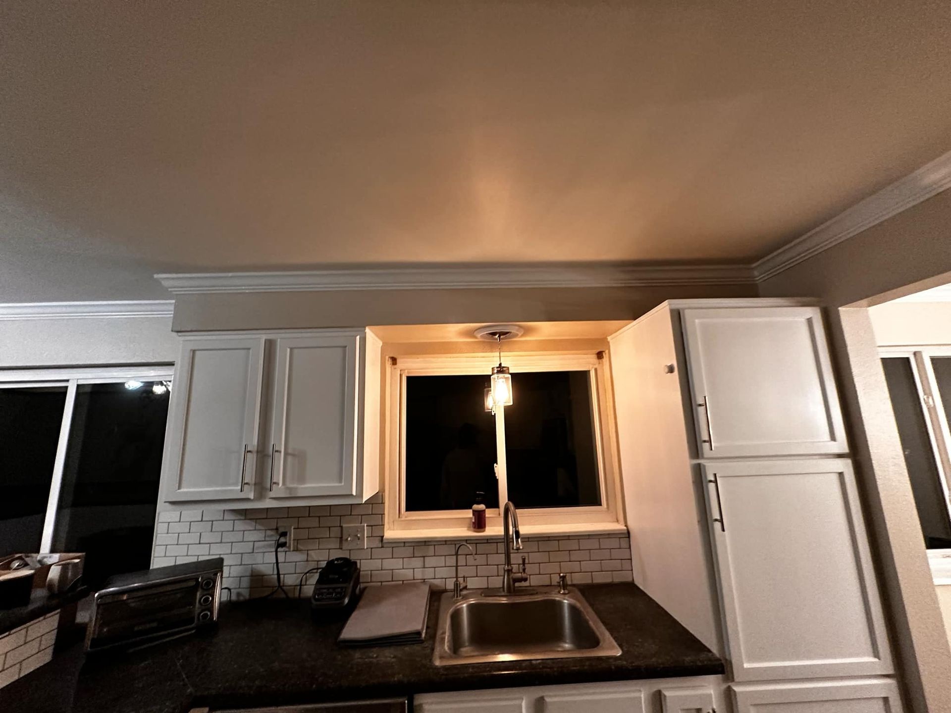 A kitchen with white cabinets a sink and a window