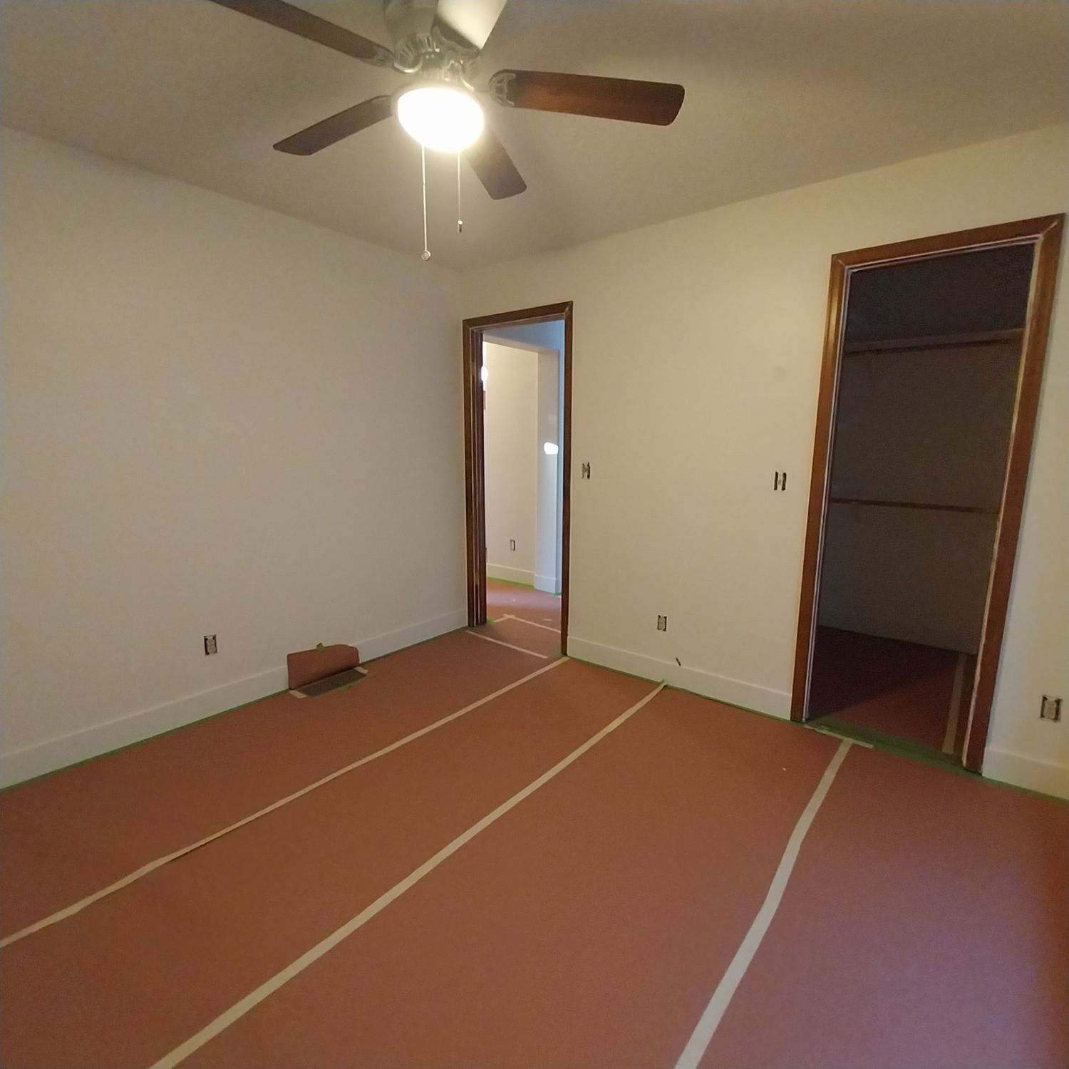 An empty room with a ceiling fan and a red carpet