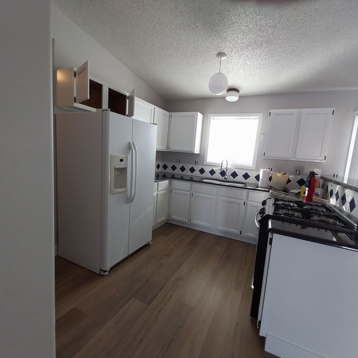 A kitchen with white cabinets and a white refrigerator