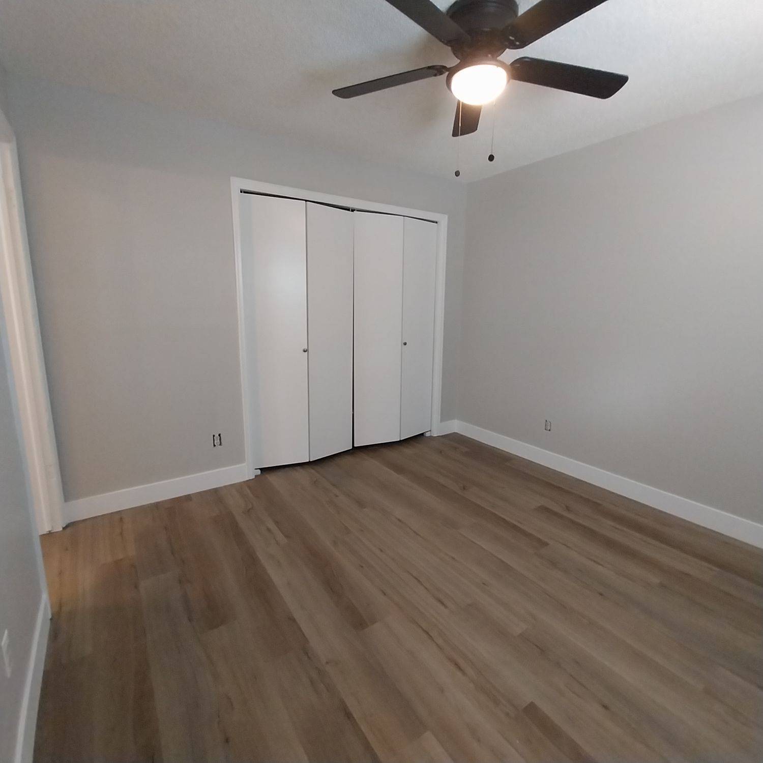 A bedroom with hardwood floors and a ceiling fan