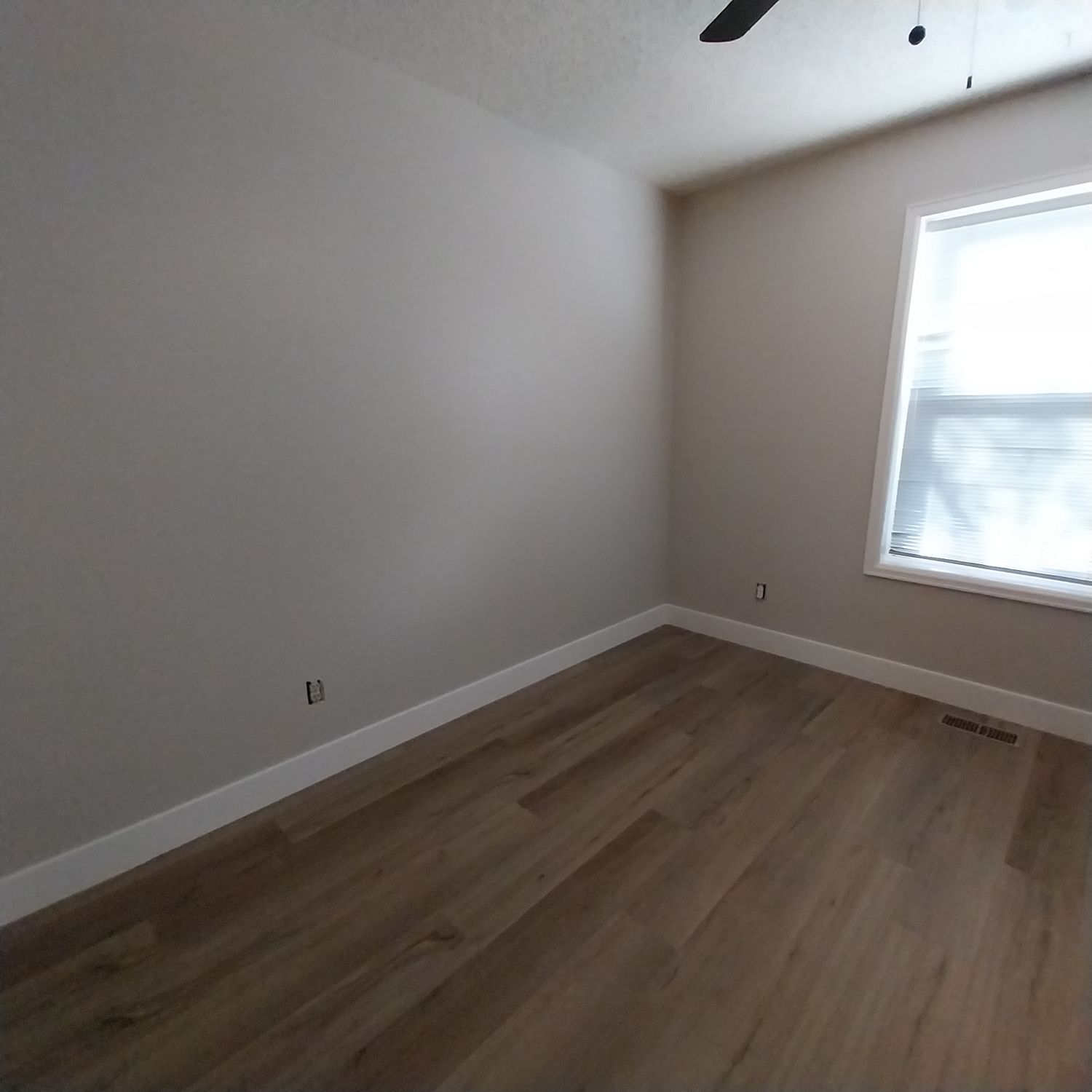 An empty room with a window and a ceiling fan