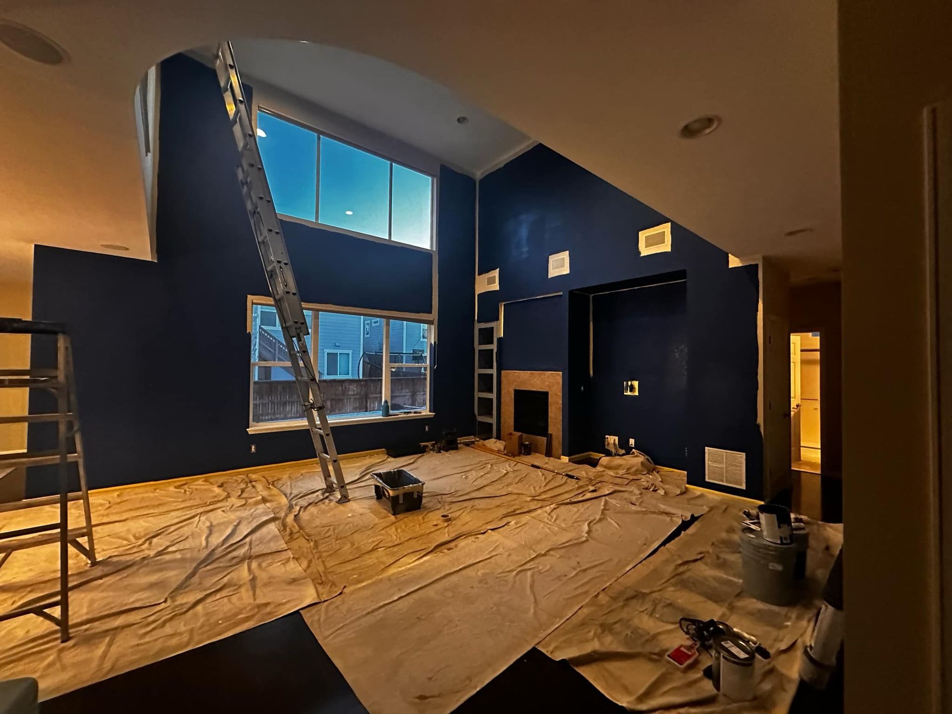 A living room with blue walls and a ladder in it