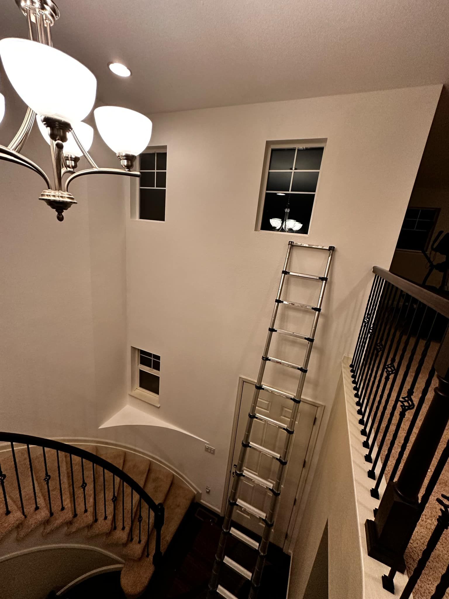 A spiral staircase with a ladder and a chandelier hanging from the ceiling