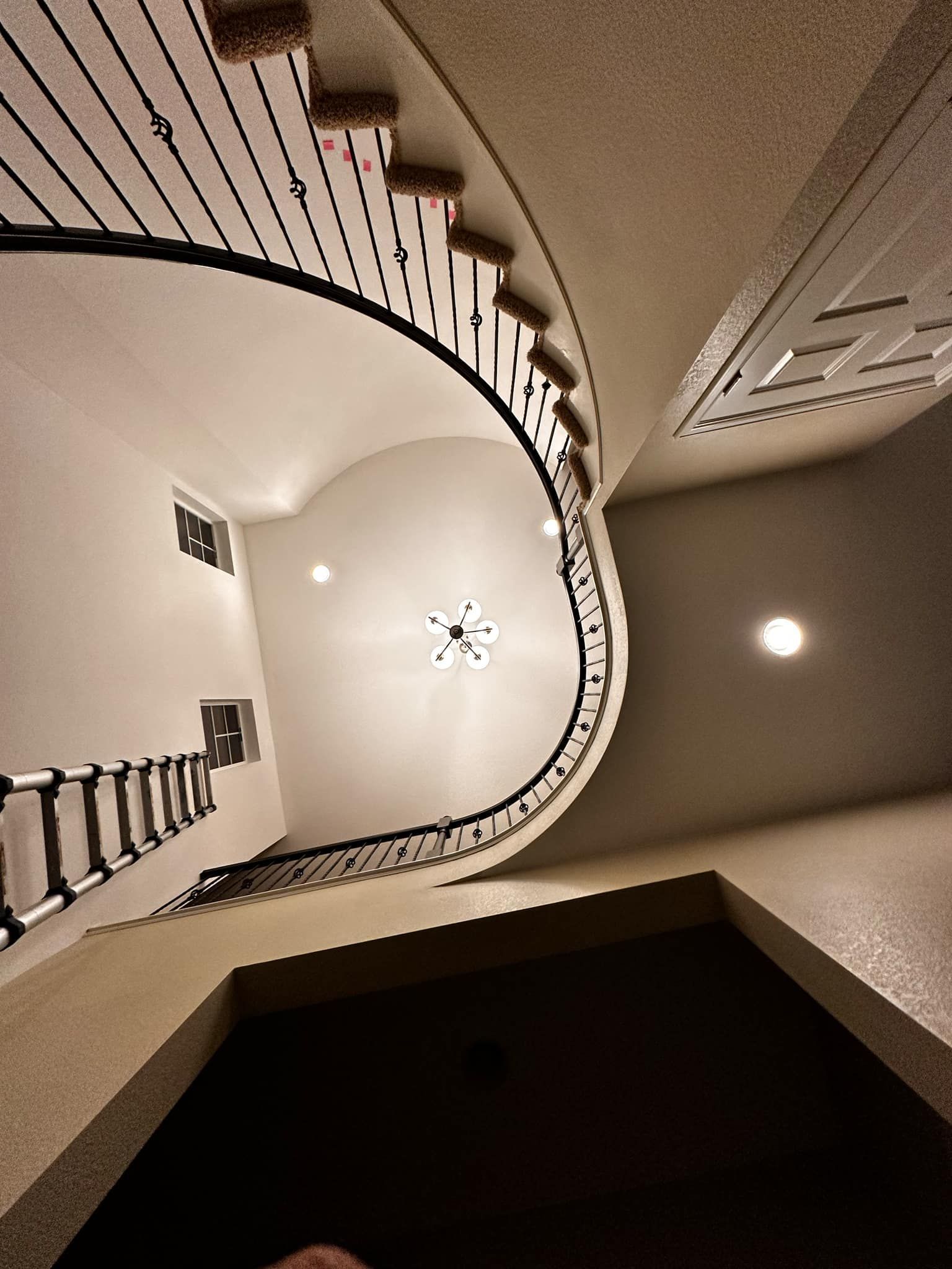 Looking up at a spiral staircase with a clock on the wall