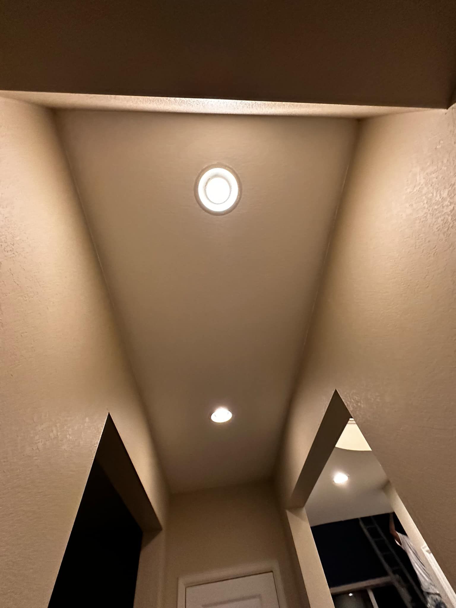 A hallway with a light on the ceiling and a door.
