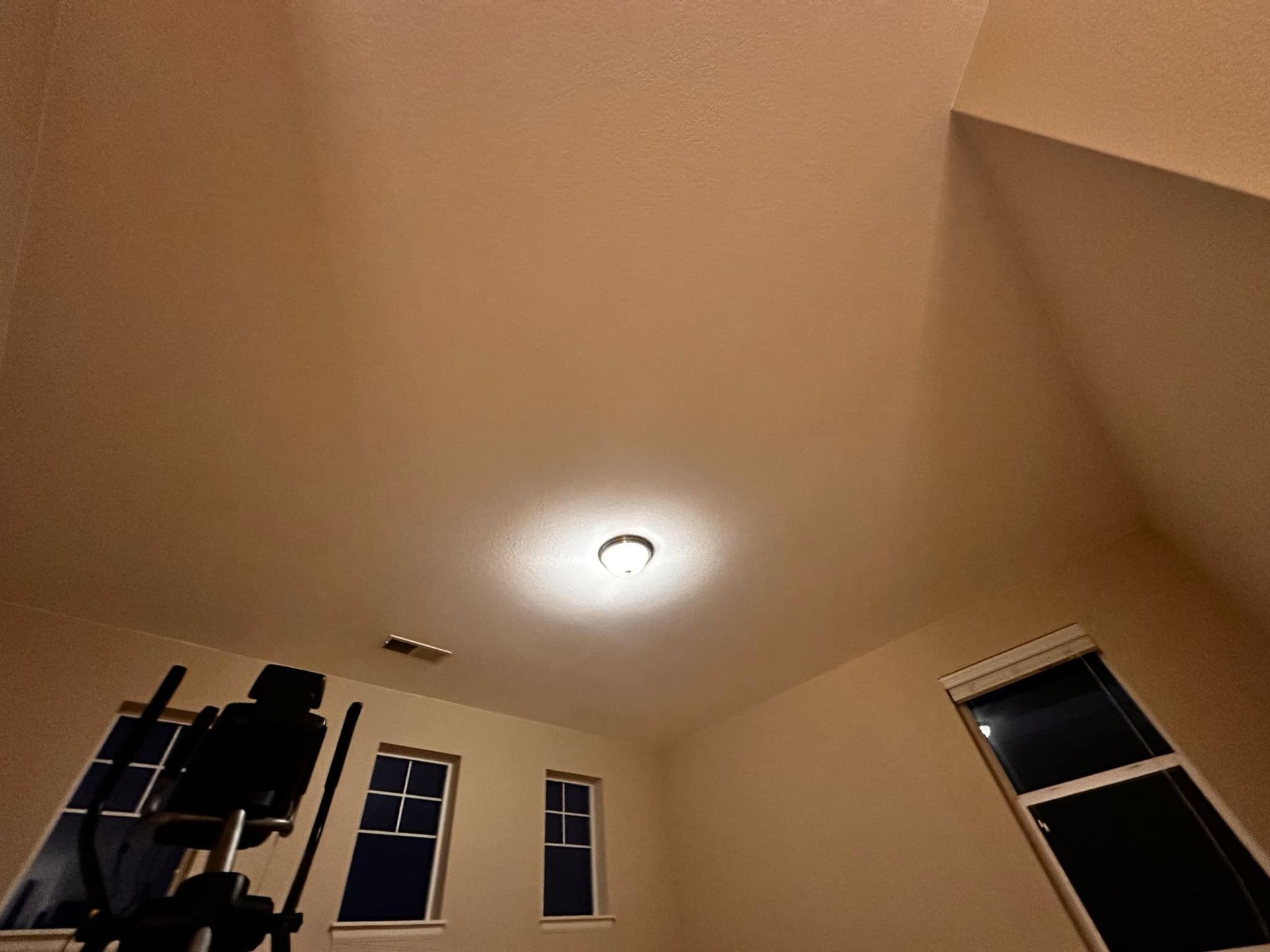 A room with a ceiling light and a few windows