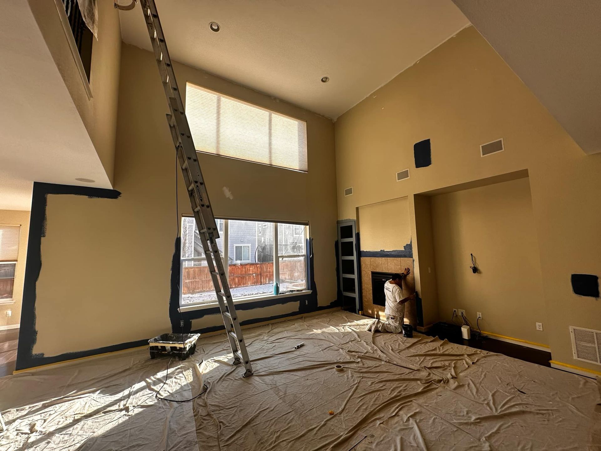 An empty living room with a ladder in the corner.