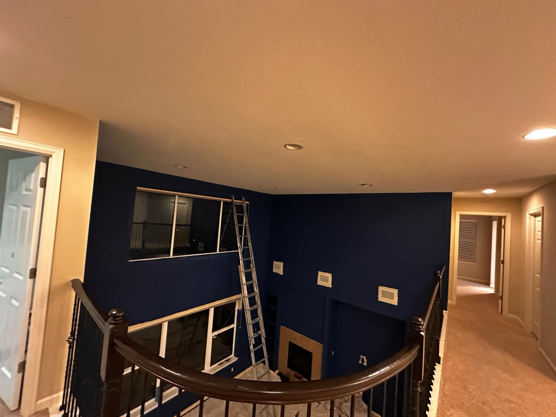 A staircase in a house with blue walls and a ladder.