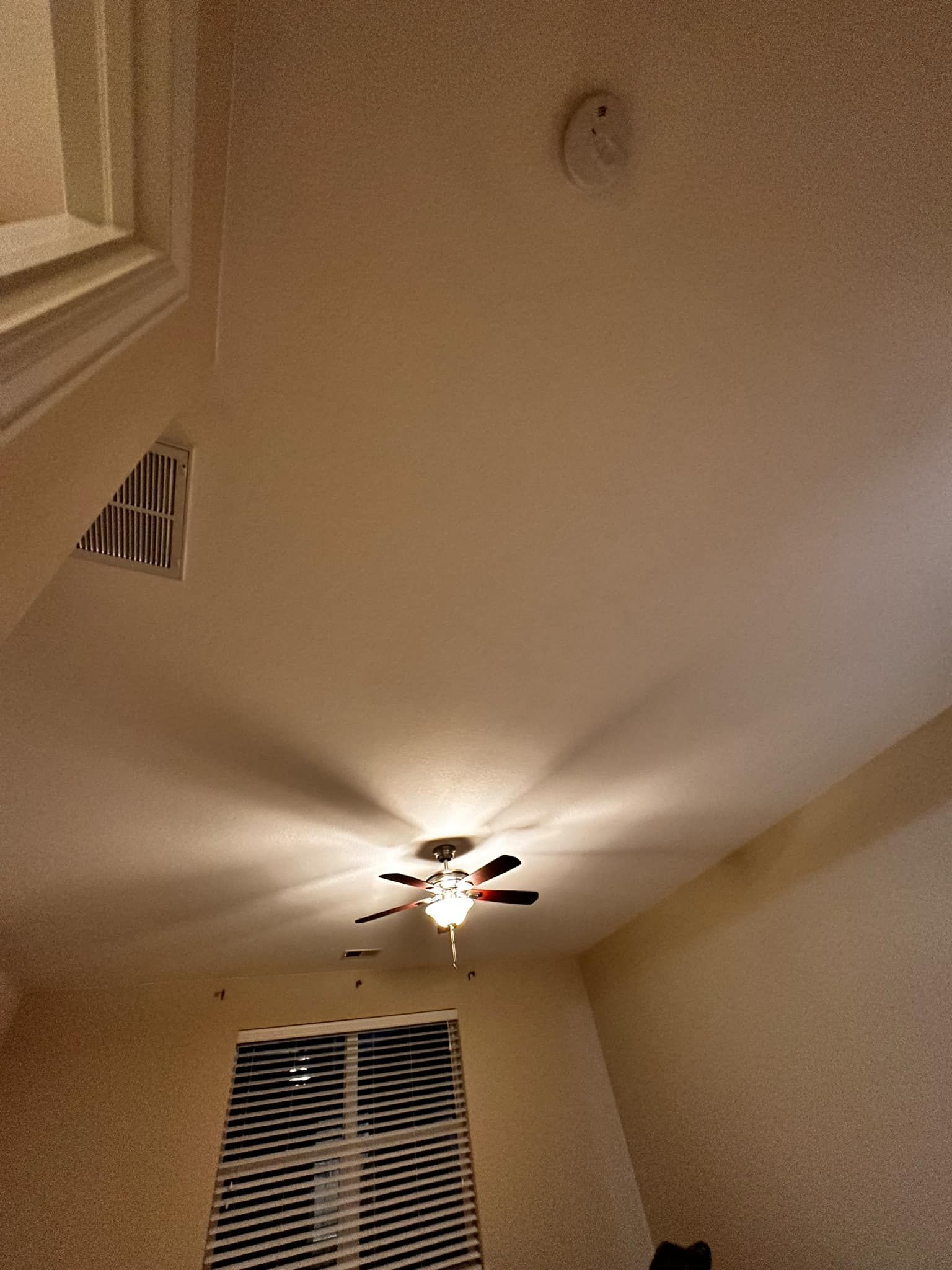 A bedroom with a ceiling fan and a window with blinds.