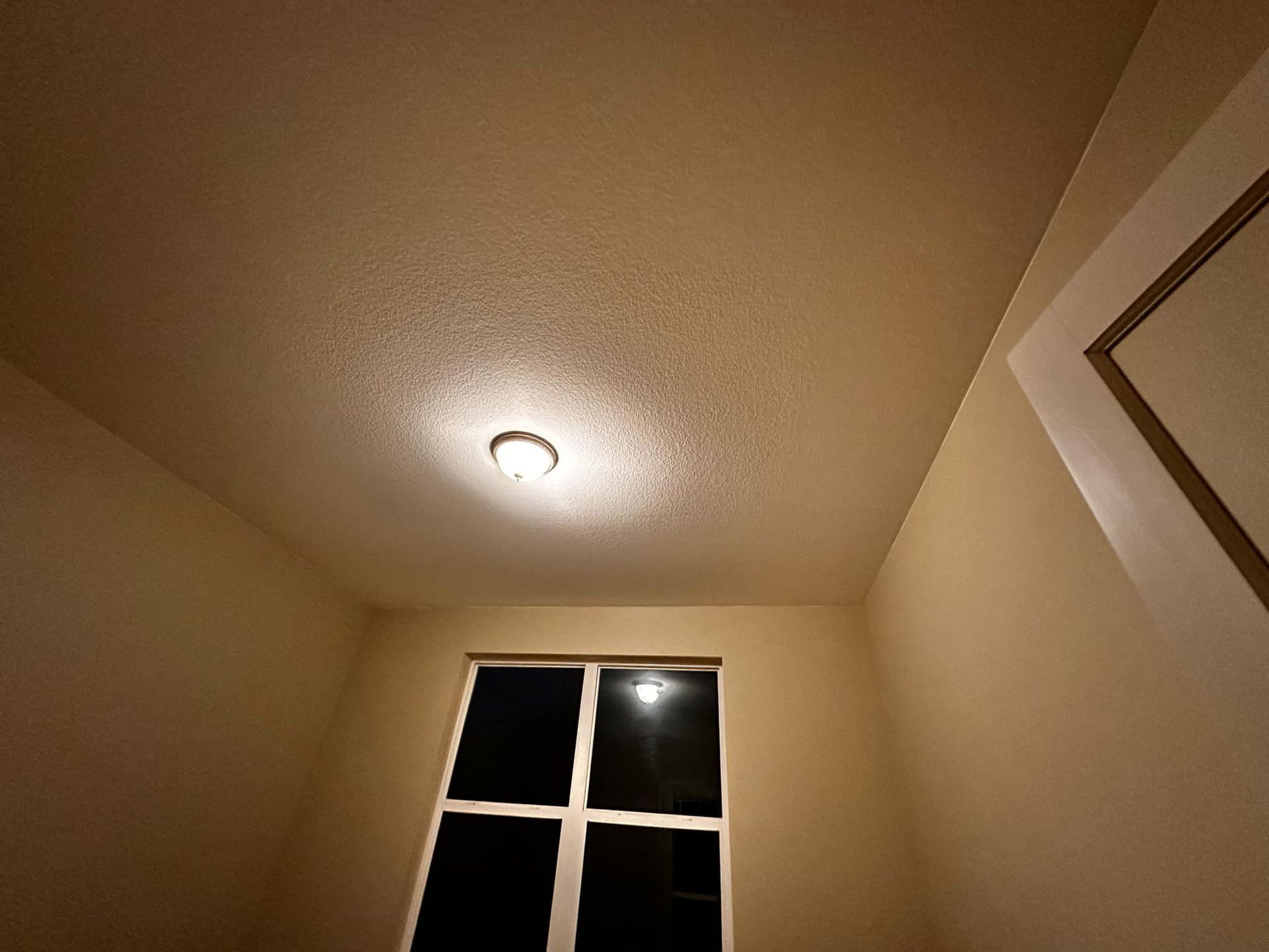 A room with a window and a light on the ceiling.
