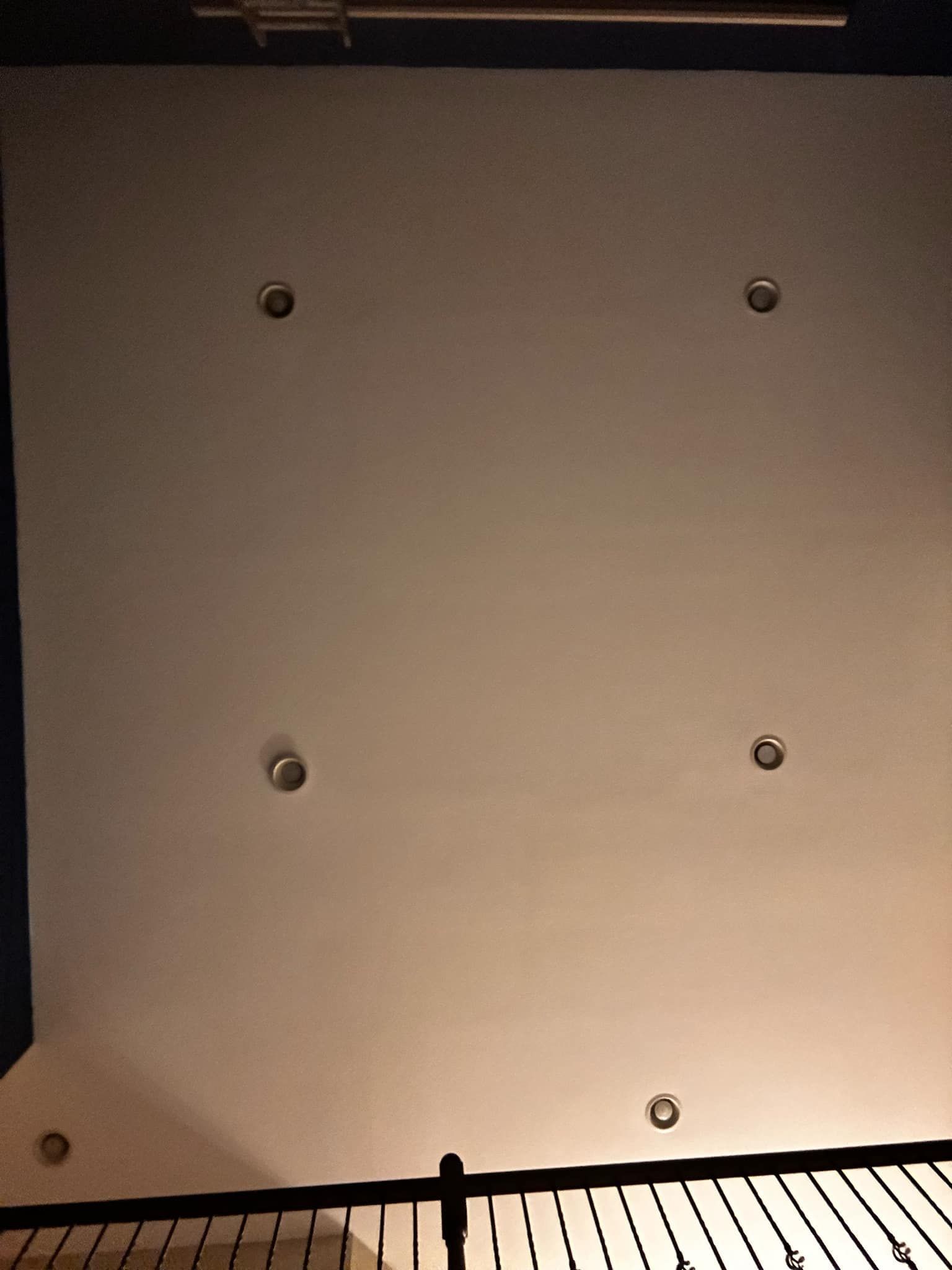 A white ceiling with a black railing and a few lights on it