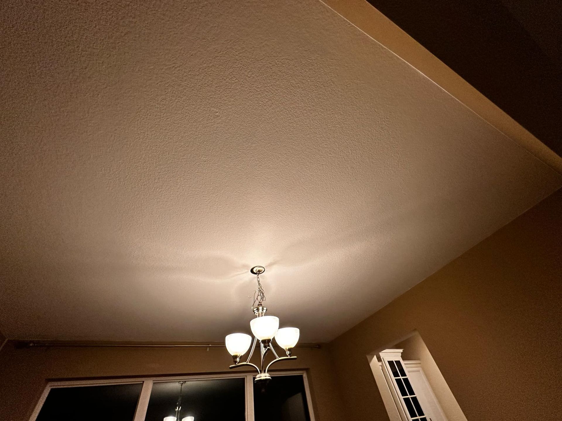 A chandelier is hanging from the ceiling in a room with a window.