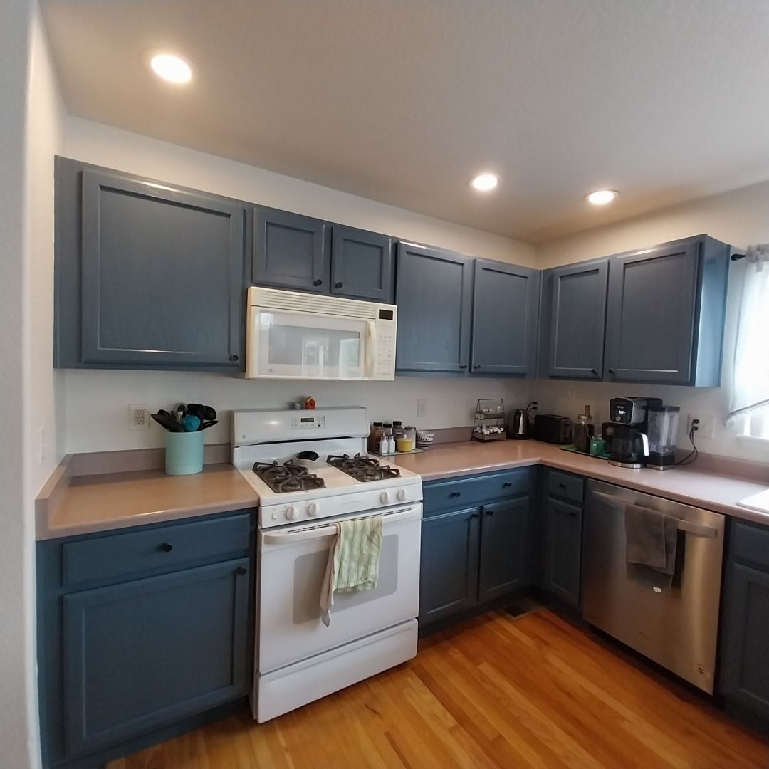 A kitchen with blue cabinets and a white stove top oven