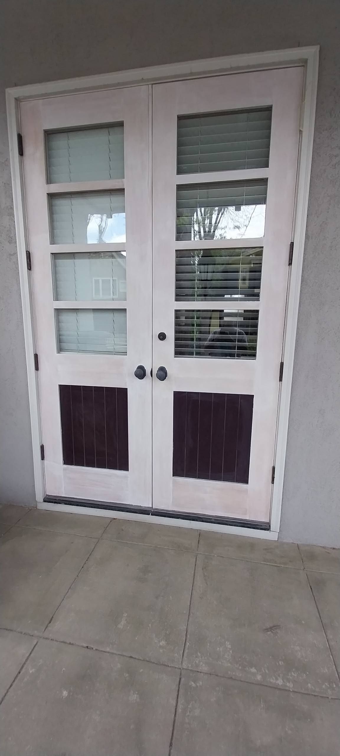 A pair of french doors are sitting on top of a concrete porch.