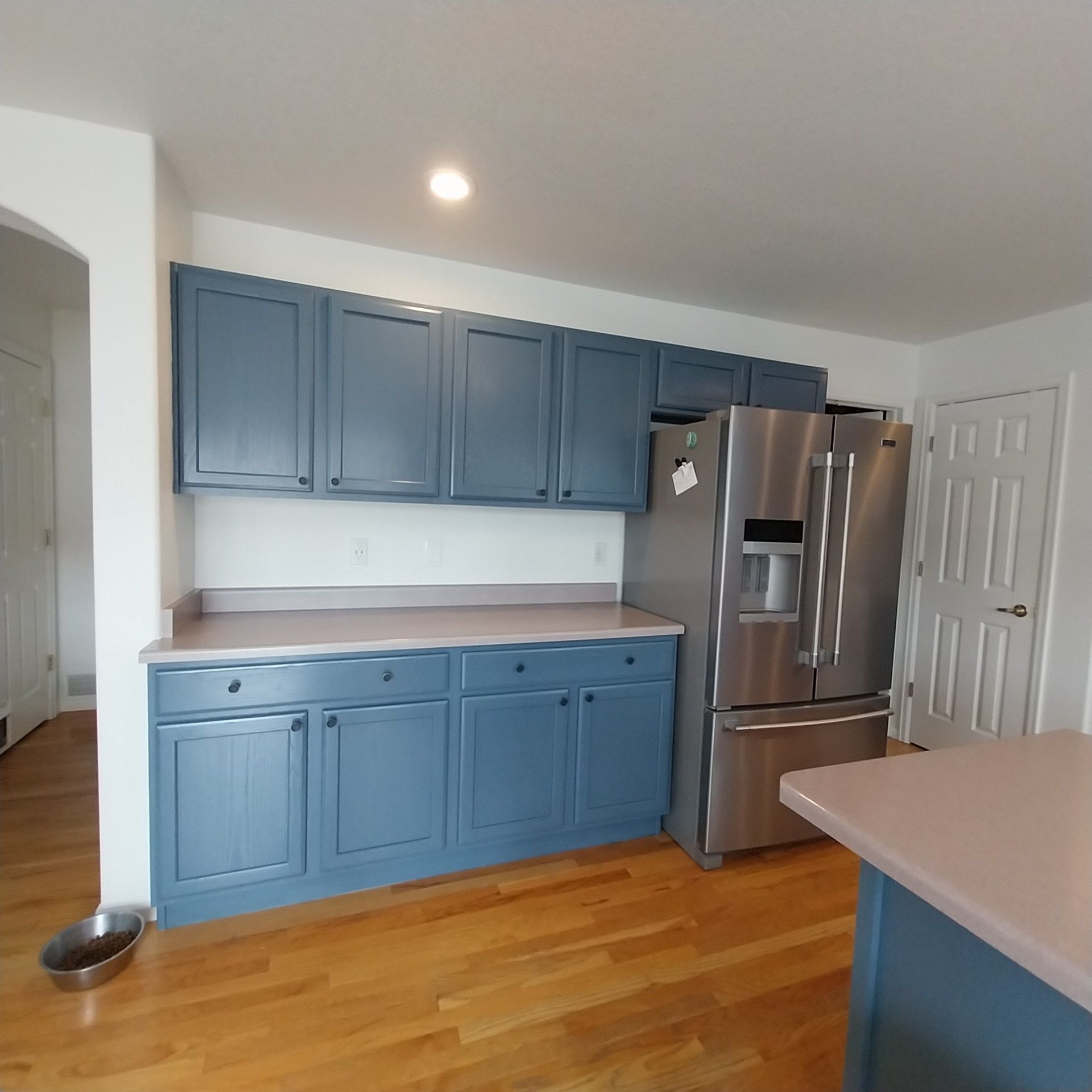 A kitchen with blue cabinets and a stainless steel refrigerator