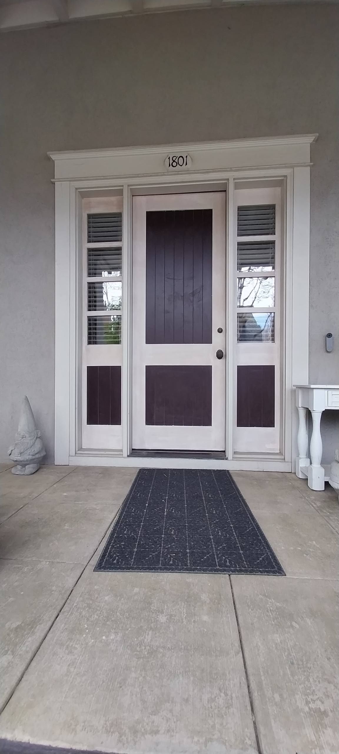 The front door of a house with a black mat leading to it.