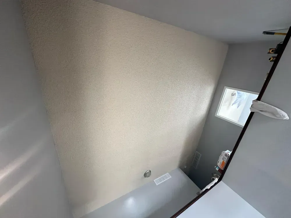 A bathroom with a toilet , sink , mirror and window.