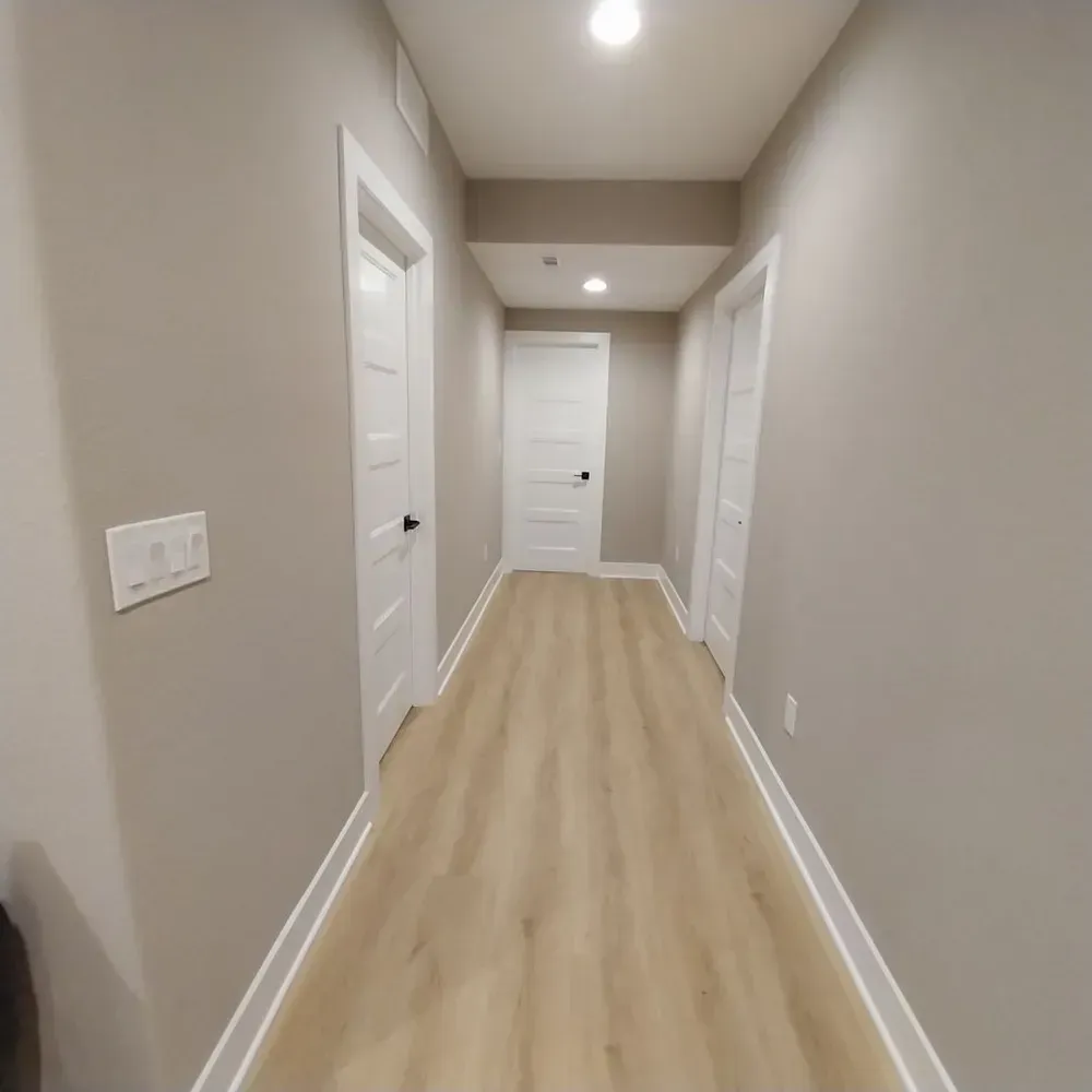 A long hallway with hardwood floors and gray walls