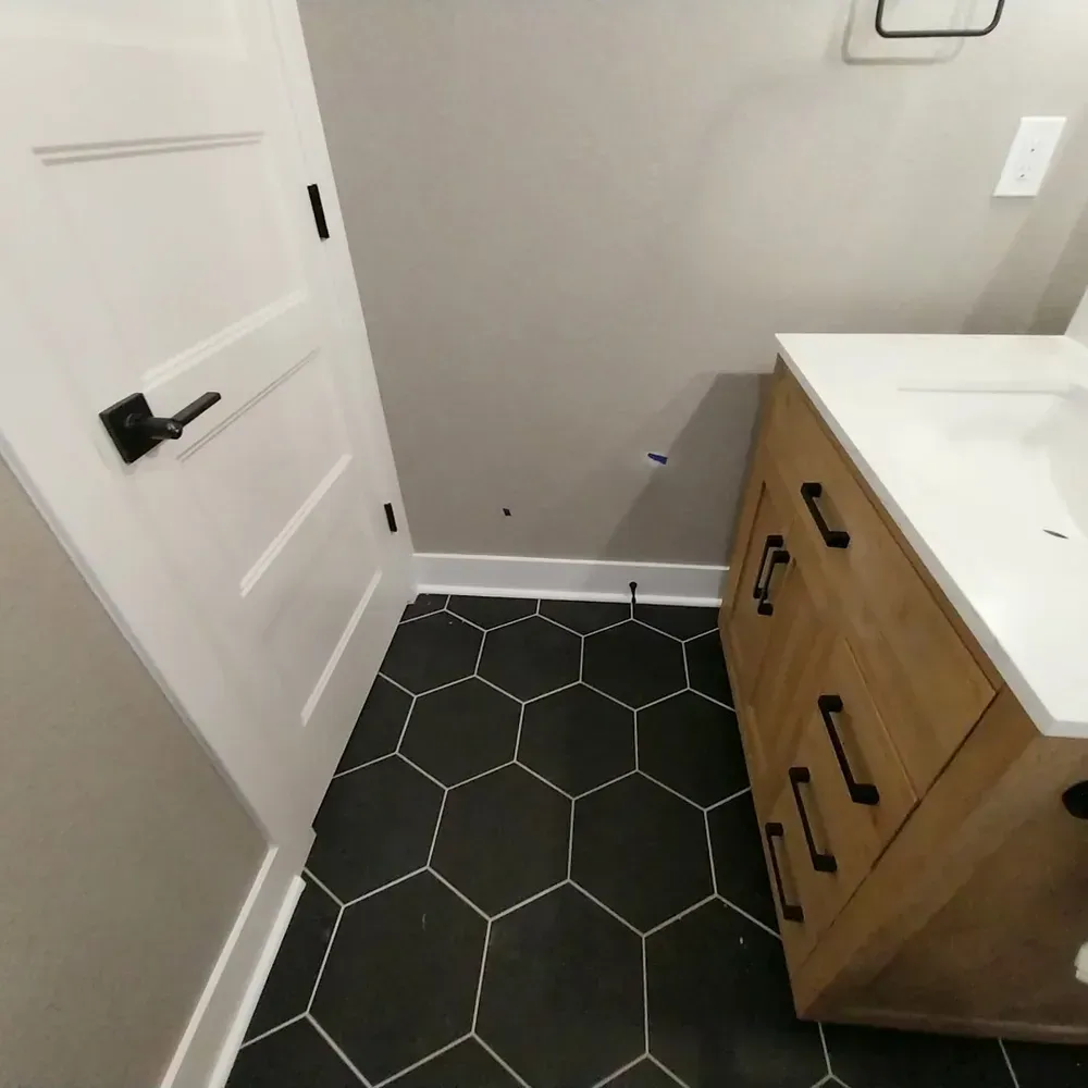 A bathroom with black tiles and a wooden vanity