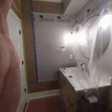 A bathroom with a sink and a shower covered in plastic.
