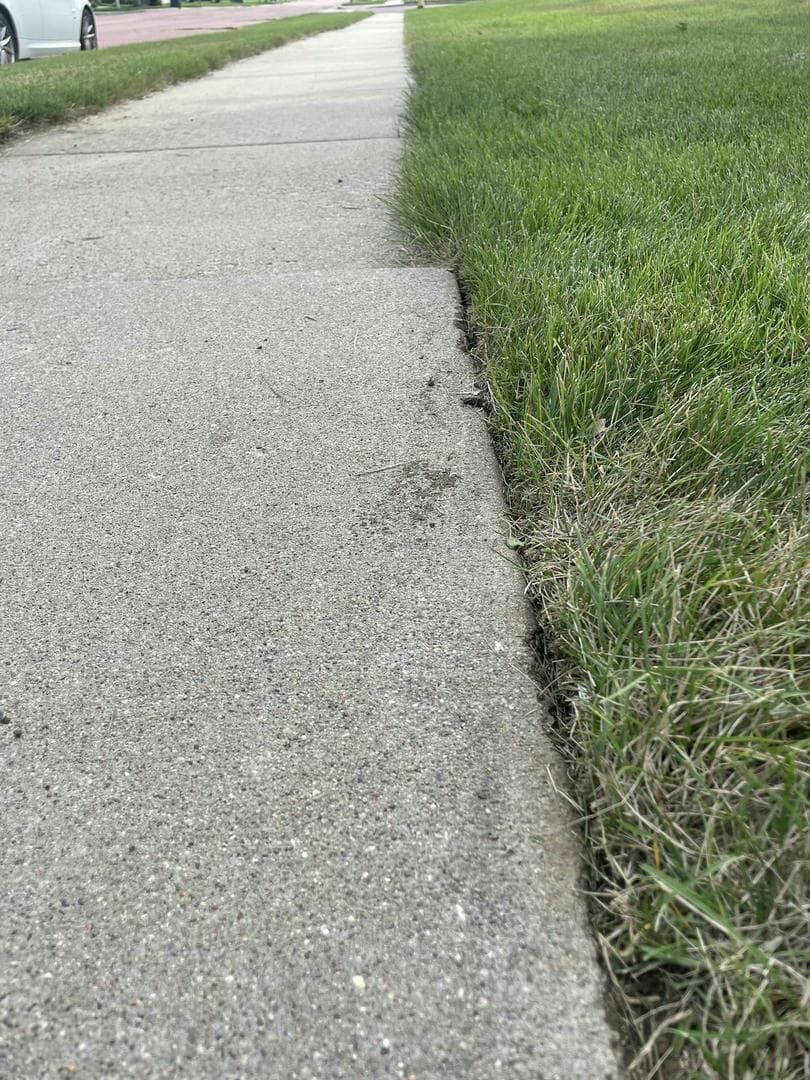 Concrete sidewalk next to green grass.