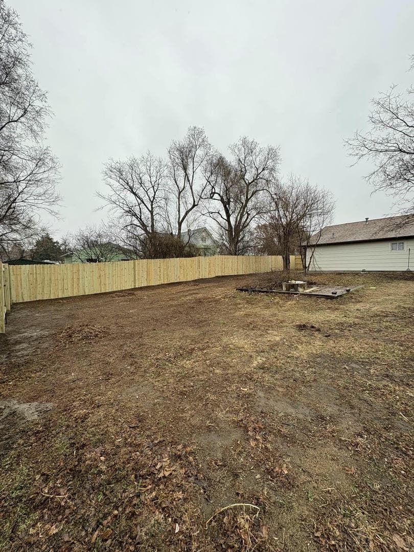 A newly fenced backyard with bare ground under an overcast sky.