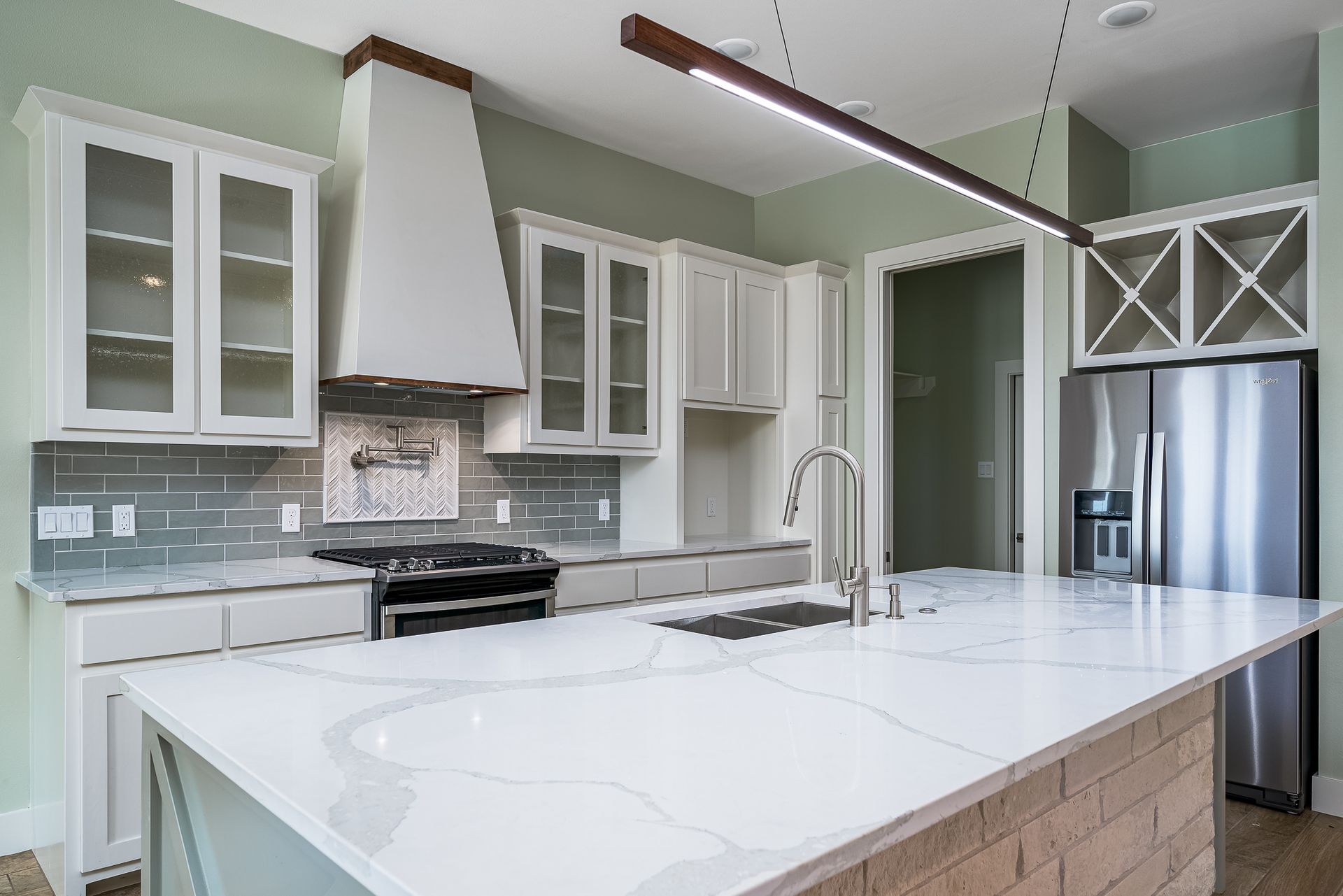 A kitchen with white cabinets , stainless steel appliances , and a large island.