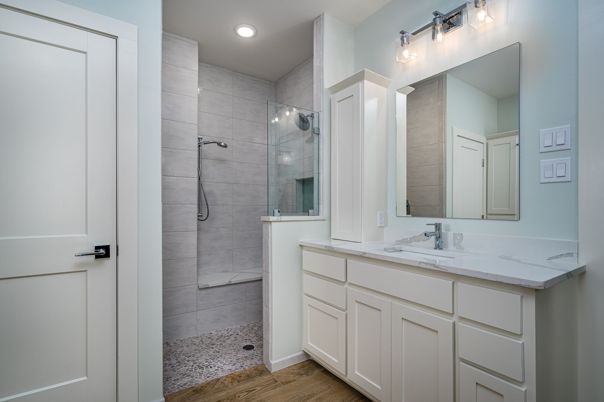 A bathroom with a sink , mirror and walk in shower.