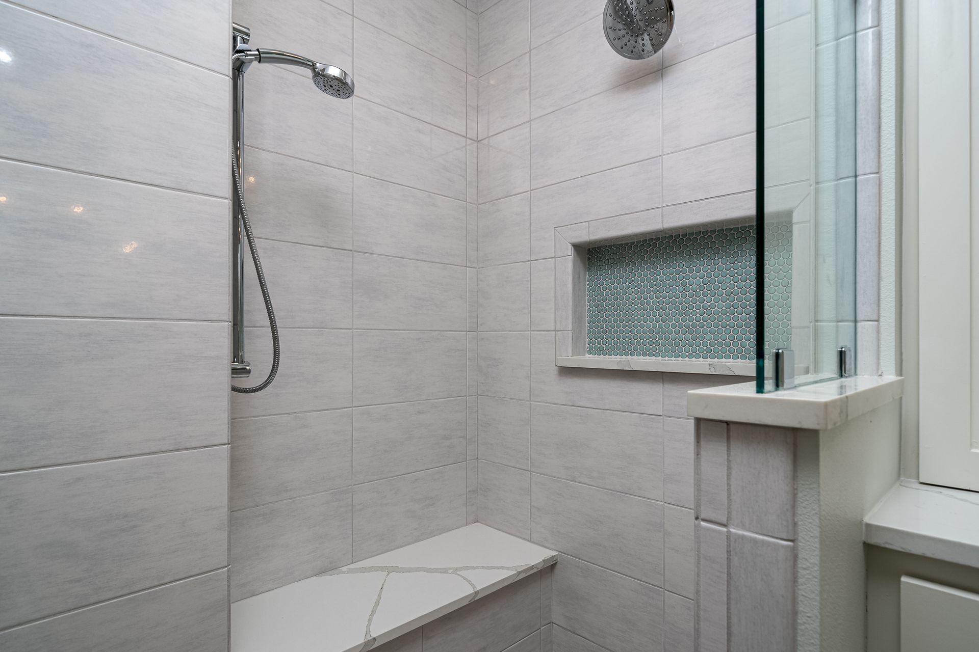 A bathroom with a walk in shower and a bench.