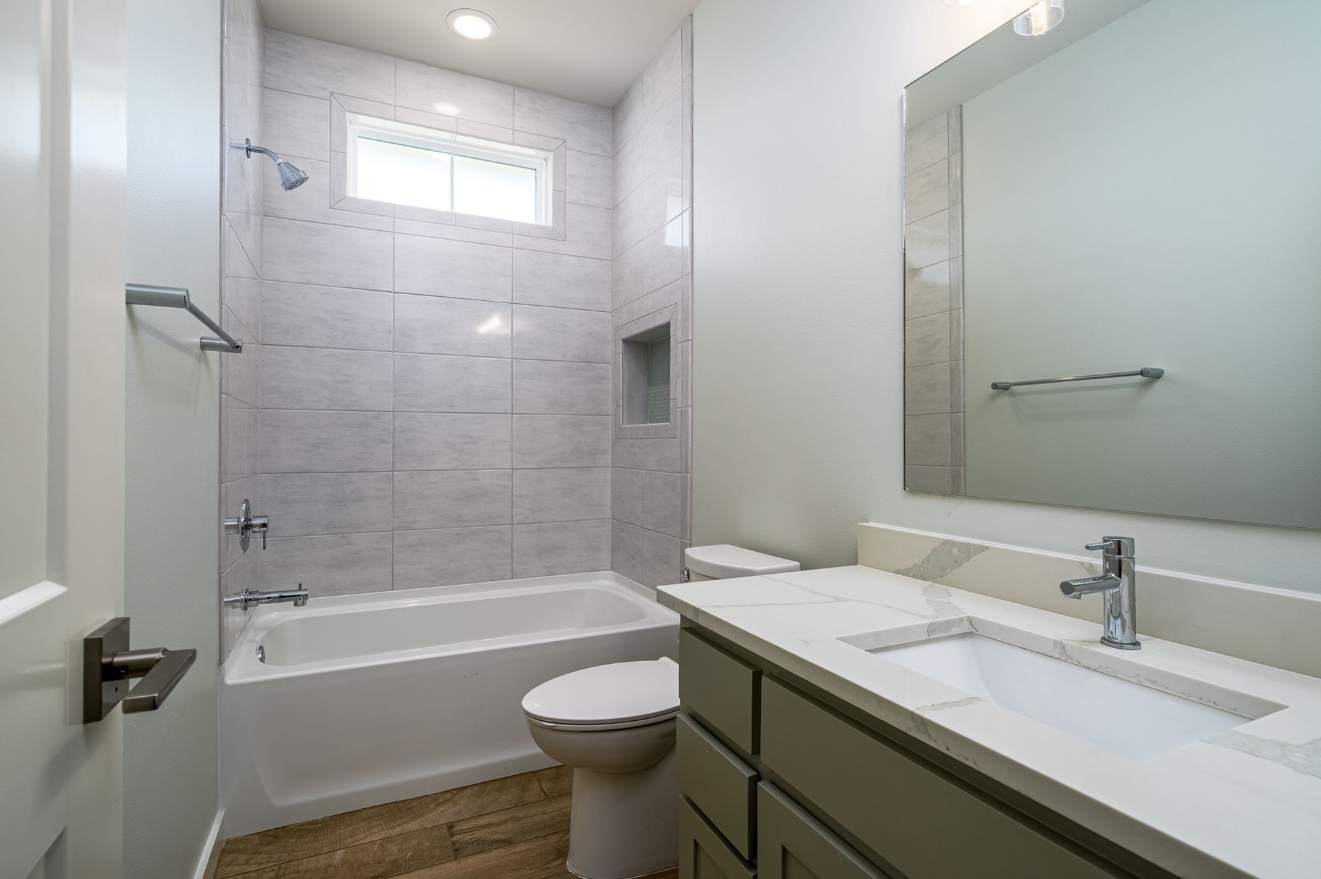 A bathroom with a tub , toilet , sink and mirror.