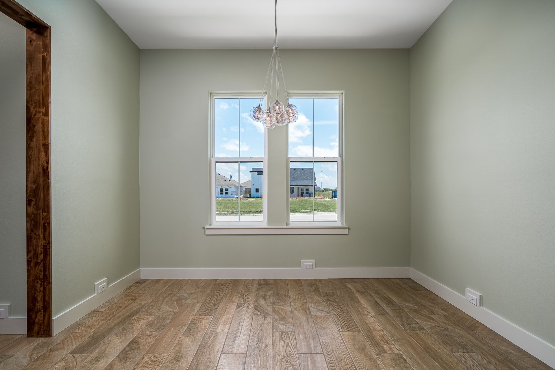 An empty room with two windows and a chandelier.