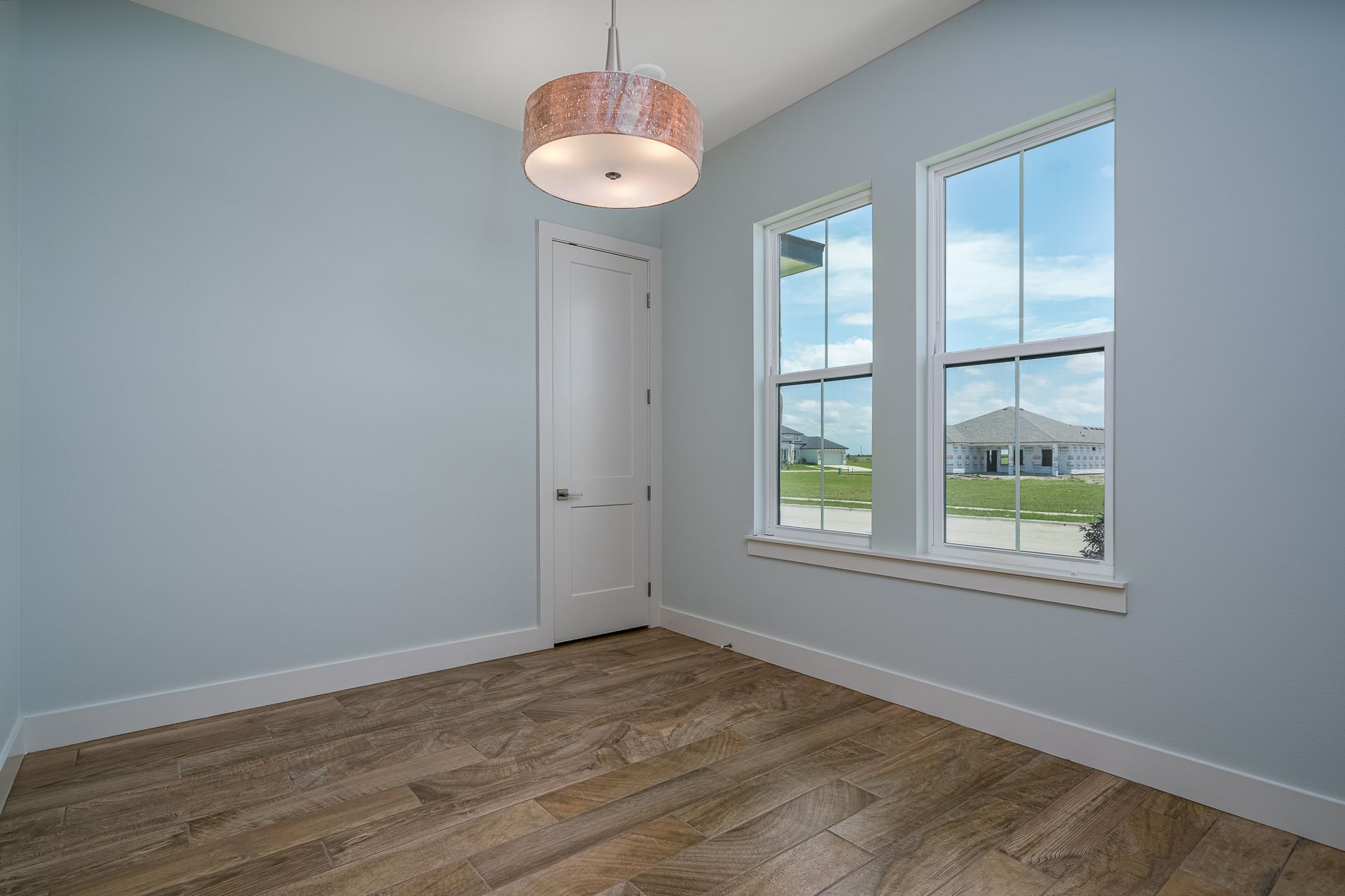 An empty room with two windows and a chandelier.