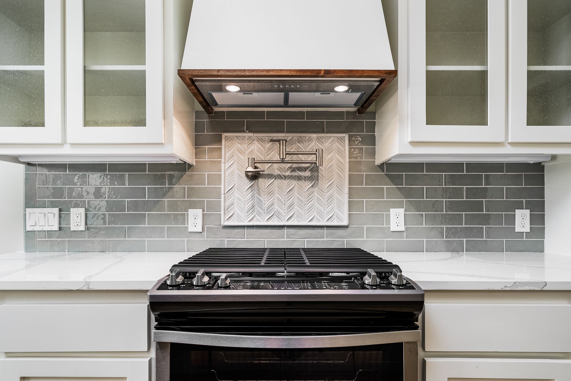 A kitchen with a stove and a hood above it.