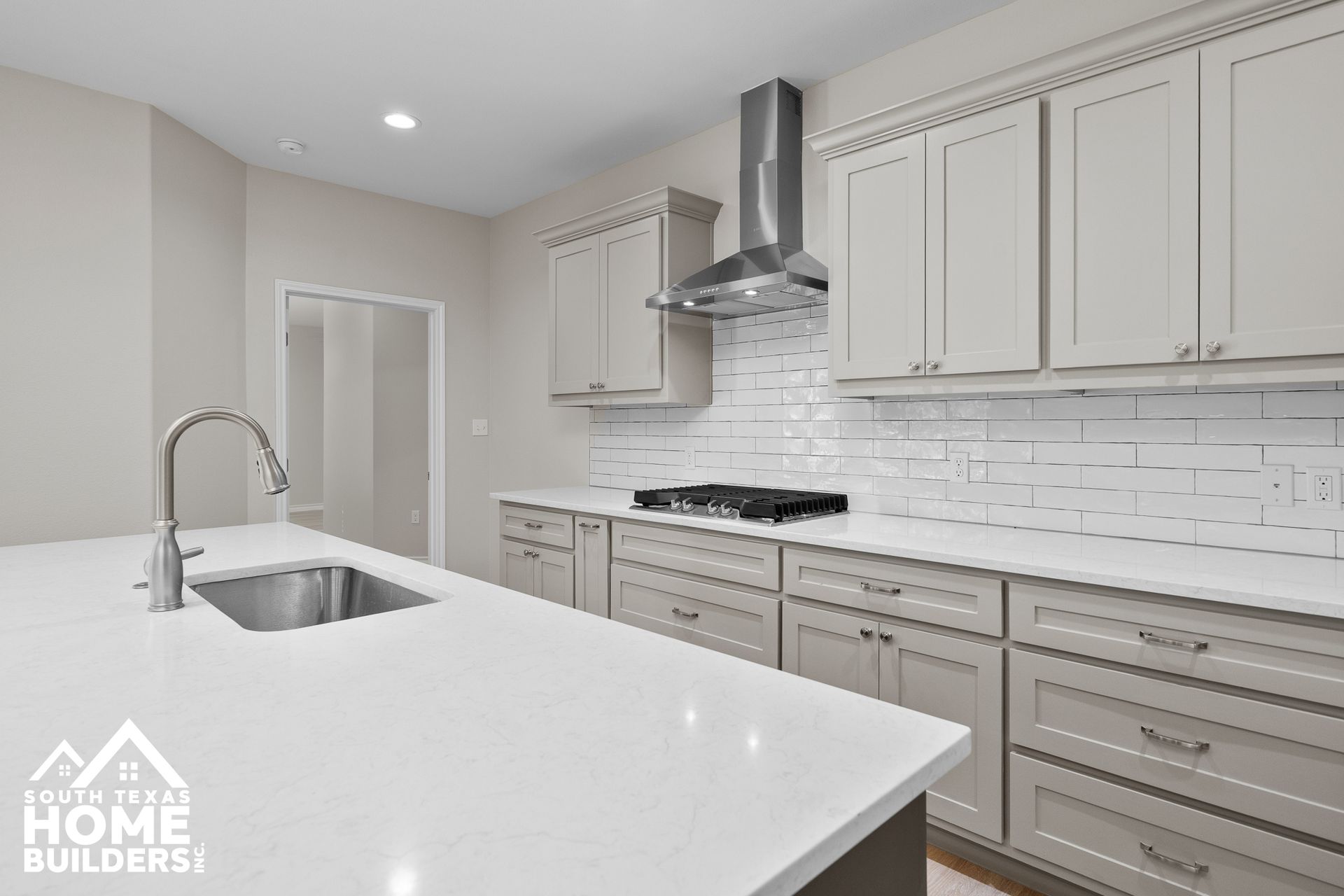 Modern kitchen with light gray cabinets, white countertops, and stainless steel appliances.