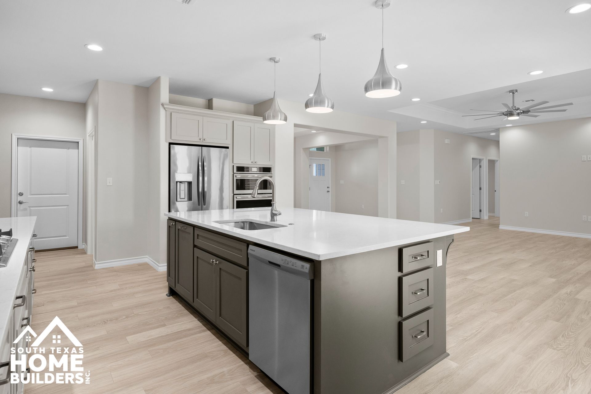 Modern kitchen with gray island, stainless steel appliances, and white countertops.