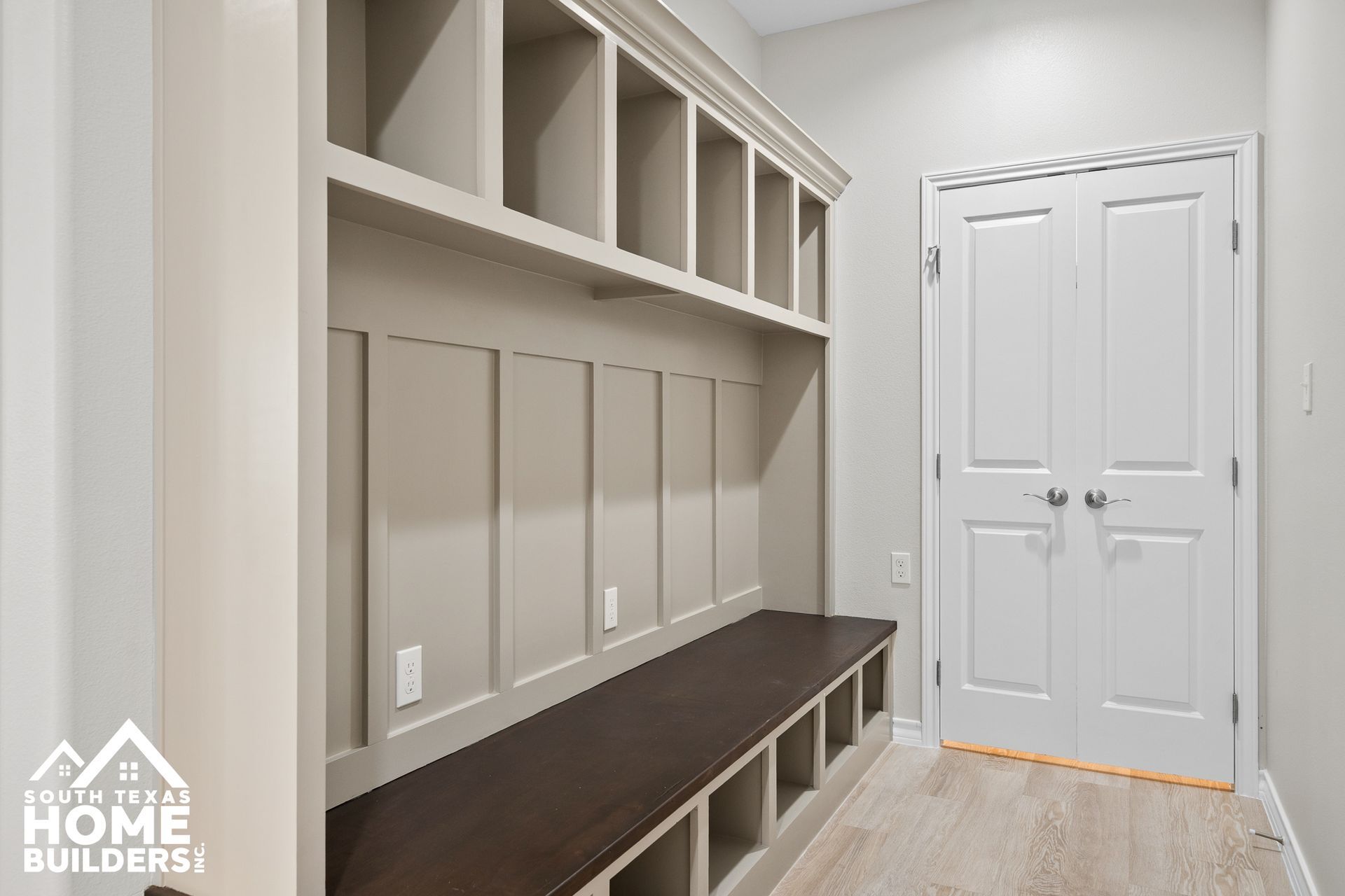 Built-in mudroom with shelves, bench, and storage cubbies. White door on the right.