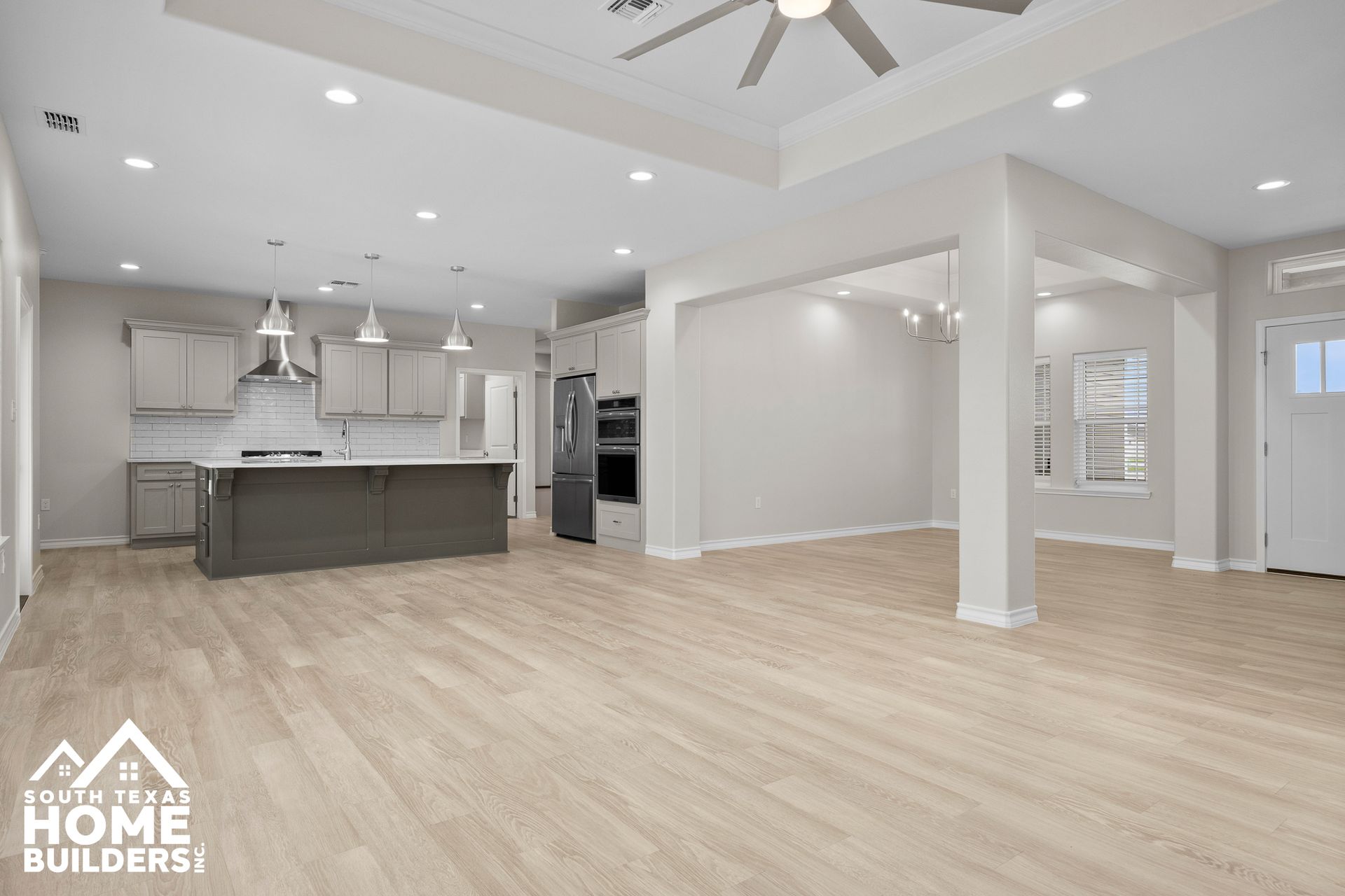 Open-concept kitchen and living area with light wood floors and gray cabinetry.