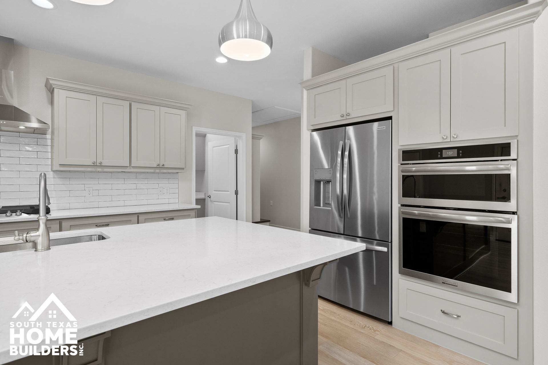 Modern kitchen with white countertops, gray cabinets, stainless steel appliances, and a central island.