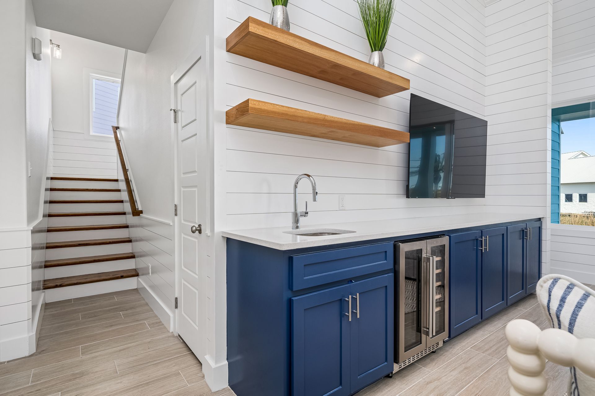A kitchen with blue cabinets , a sink , a refrigerator and a television.
