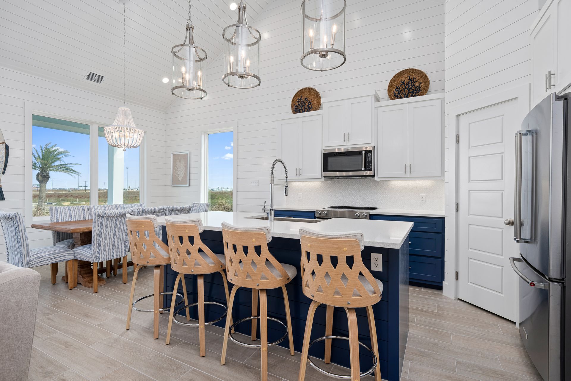A kitchen with a large island , stools and a refrigerator.
