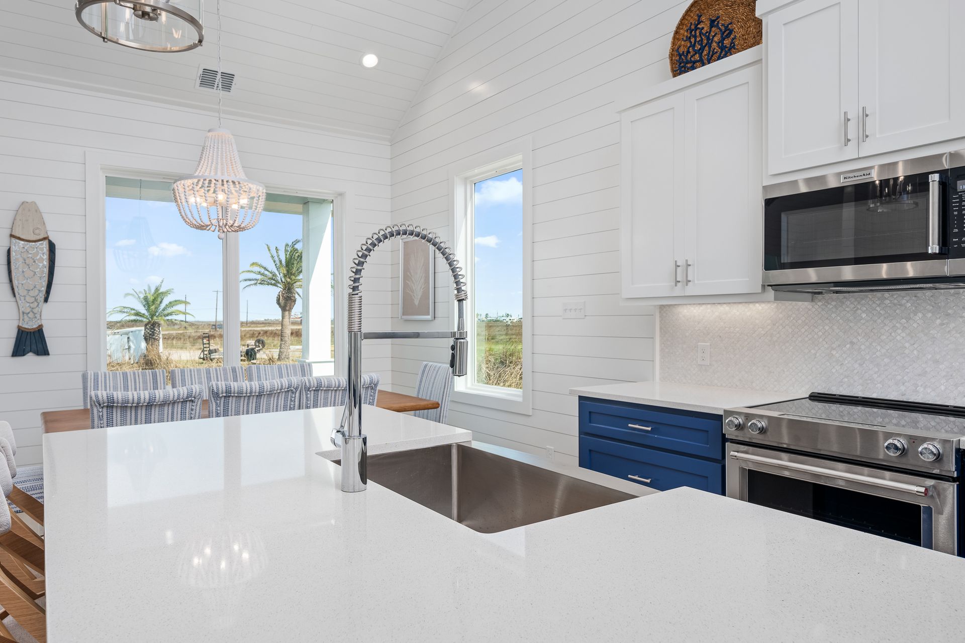 A kitchen with white cabinets , stainless steel appliances , a sink and a microwave.