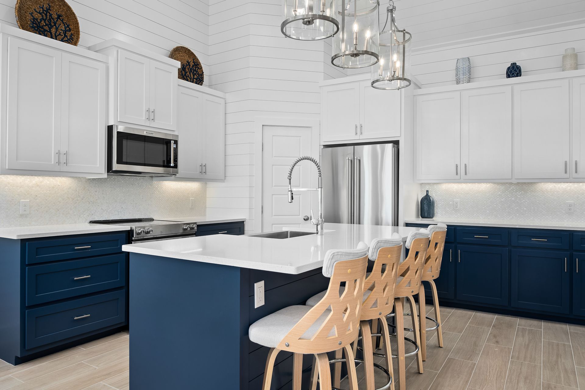 A kitchen with blue cabinets , white cabinets , stainless steel appliances and a large island.