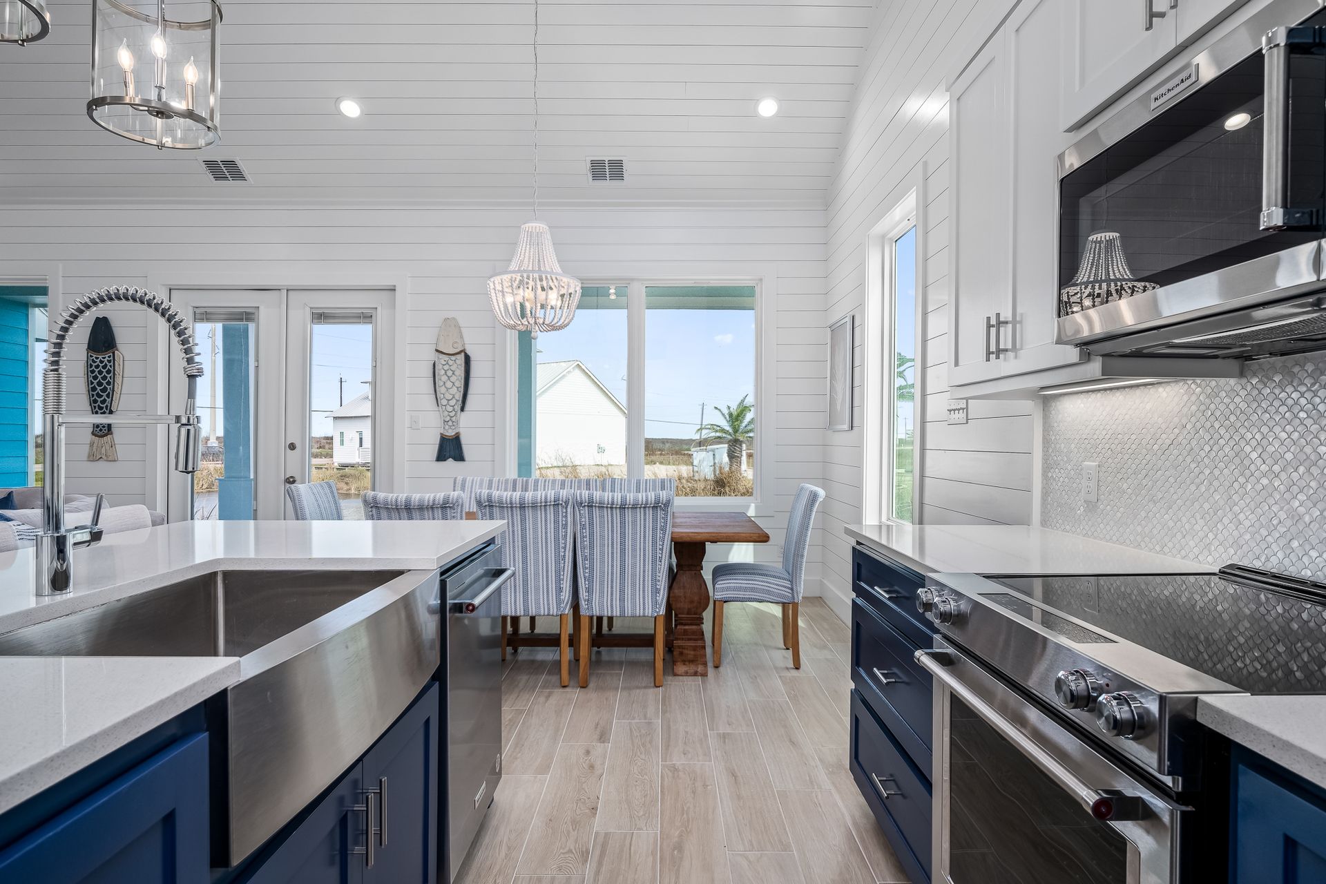 A kitchen with blue cabinets , stainless steel appliances , a sink and a microwave.