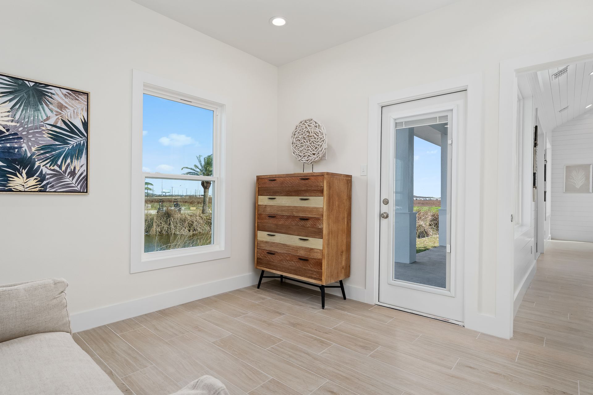 A bedroom with a dresser , two windows and a door.