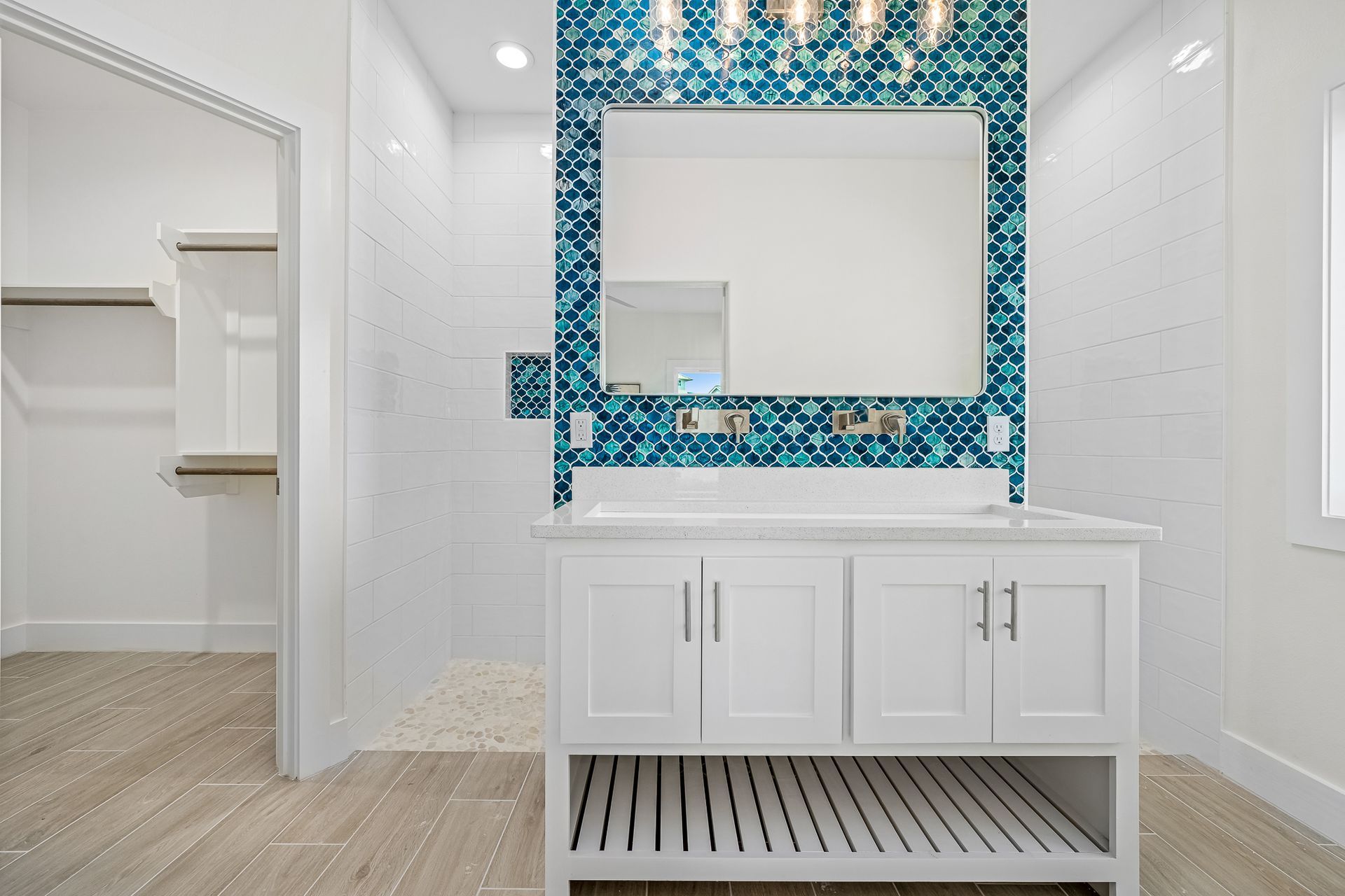 A bathroom with a sink , mirror and walk in shower.