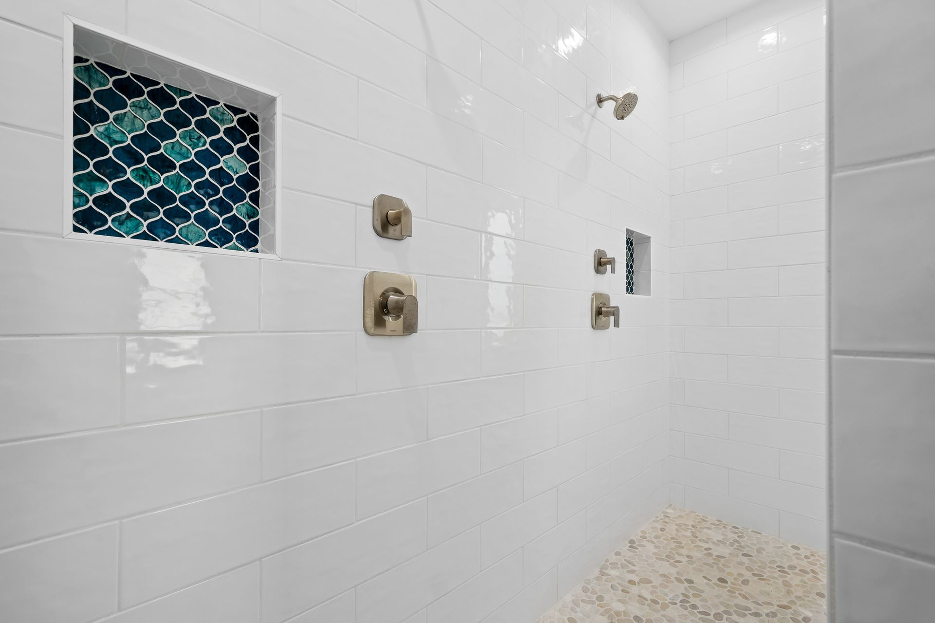 A bathroom with white tiles and a walk in shower.