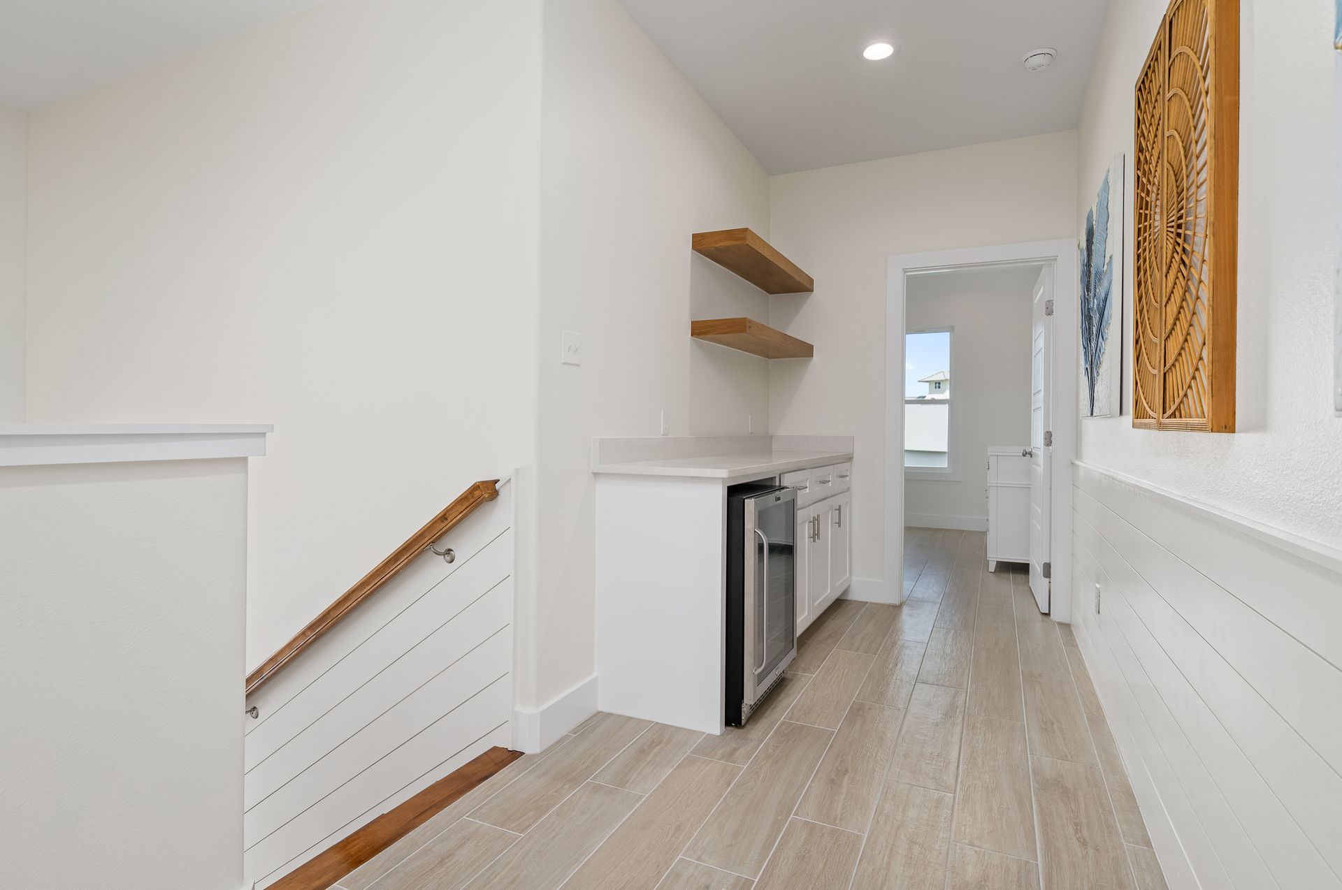 A long hallway with stairs leading up to a kitchen.