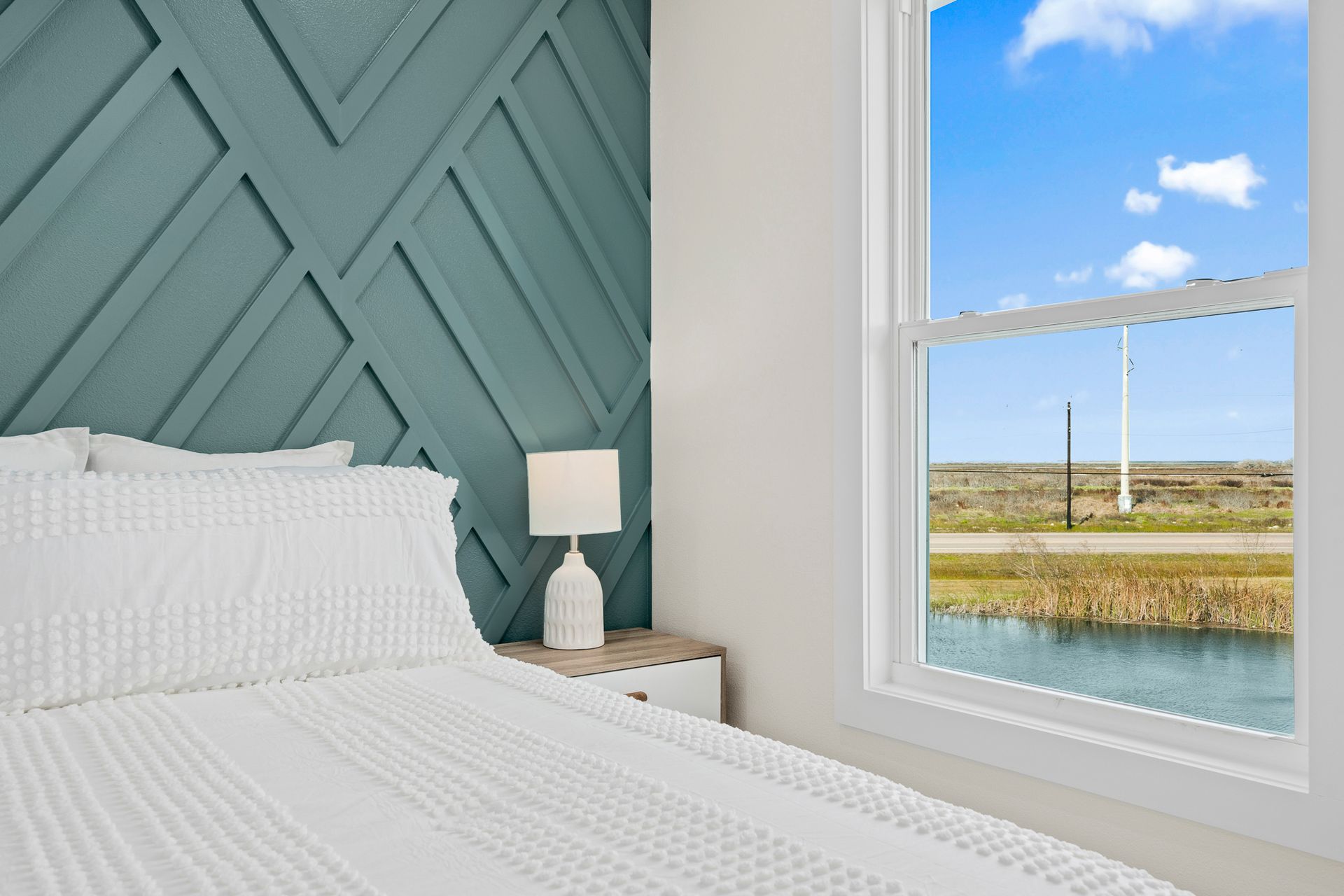 A bedroom with a bed and a window with a view of a lake.