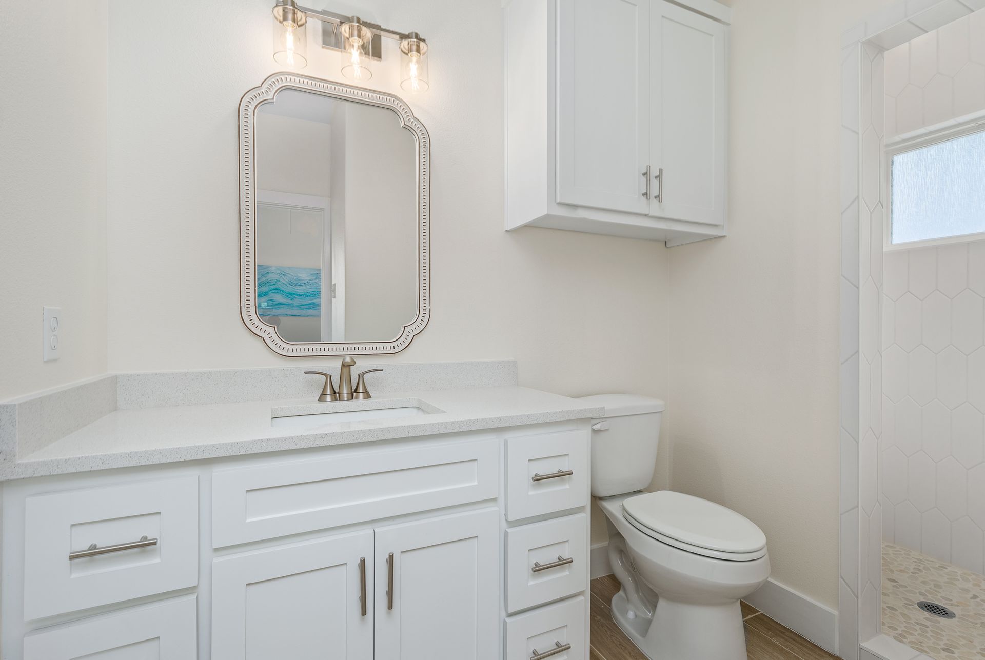 A bathroom with a sink , toilet , mirror and shower.