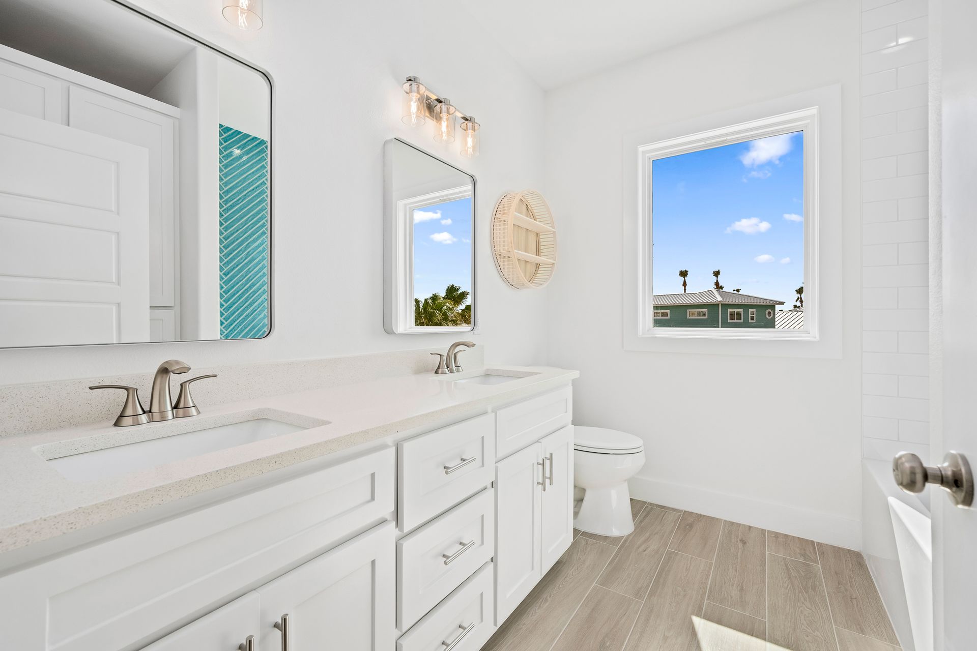 A bathroom with two sinks , a toilet , and a window.